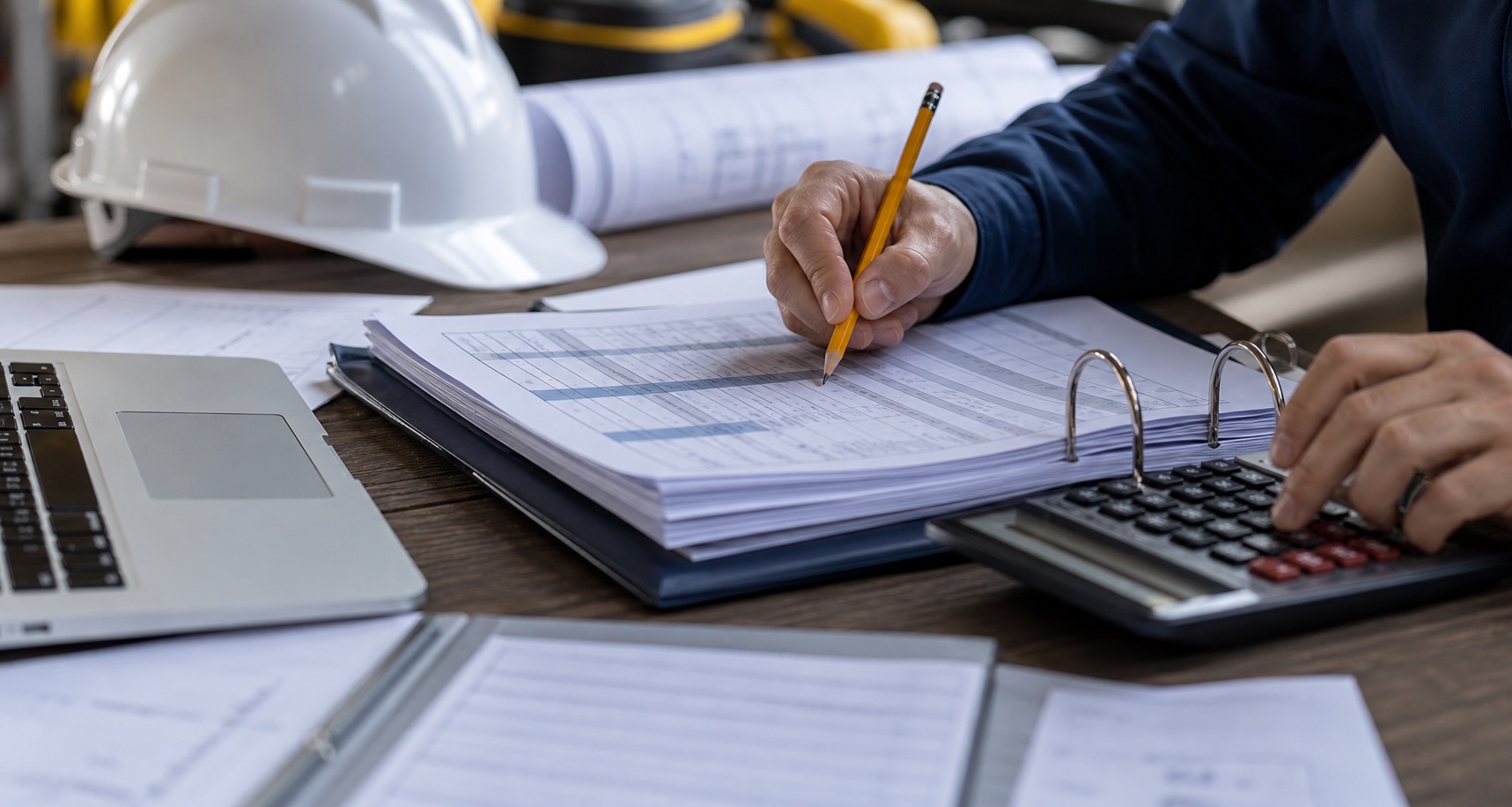 Contractor reviewing wage sheets and agreement documents at a desk